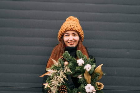 戴橙色帽子微笑的千禧一代女孩的生活方式肖像。下雪的圣诞节