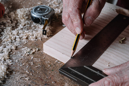 木匠用铅笔和金属正方形在桌子上测量