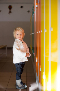 可爱的金发小男孩站在金德的储物柜前