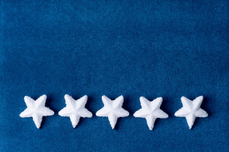 蓝色天鹅绒纸背景上有五颗白色蓬松的雪花星星照片