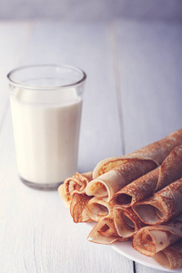 Fried pancakes rolled into a tube on a white plate. 