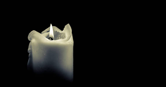 白蜡烛在黑暗中燃烧着照片
