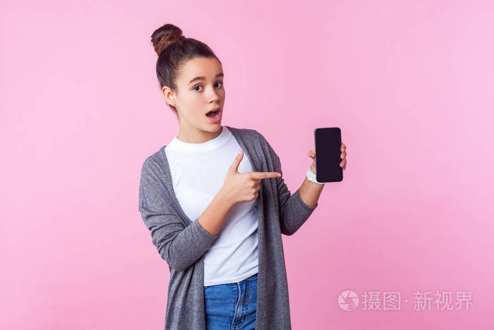 Wow, look at mobile app Portrait of surprised teenage brunette 