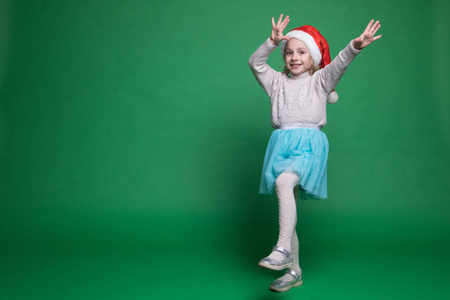 快乐的小女孩戴着圣诞老人的帽子跳