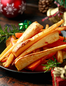 圣诞烤防风草和胡萝卜,装饰,礼品,木制乡村餐桌上的绿色树枝照片