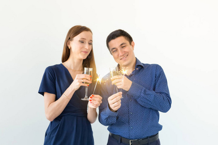 男人和女人在白色背景上用孟加拉灯和香槟酒杯庆祝圣诞或新年夜的聚会。