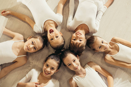 友好的小芭蕾舞演员围成一圈躺在地板上