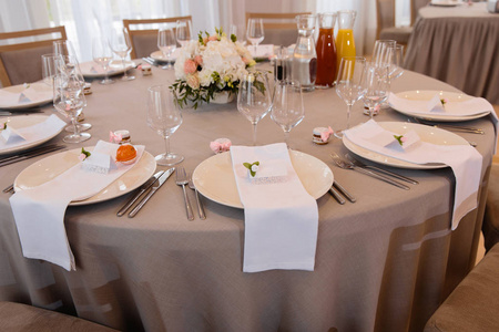 在东欧波罗的海里加拉脱维亚举行的一场婚宴上，白色大厅里的食物摆在桌上，有比格奶油和粉红色，盘子上有名字的标志小吃小吃和