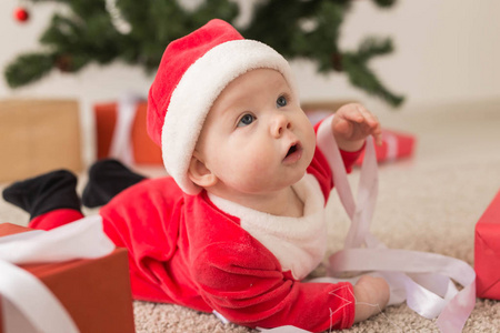 美丽的小宝宝庆祝圣诞节。新年假期。孩子穿着圣诞服装，戴着圣诞帽和礼品盒