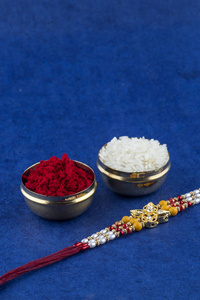 印度节日以优雅的腊肠米粒和锦葵为背景。一种传统的印度腕带，象征着兄弟姐妹之间的爱。