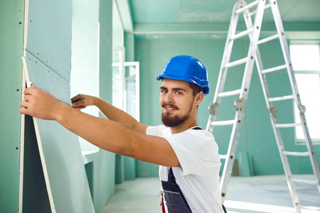 建筑工人在建筑工地安装石膏板干墙