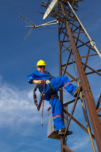 Electrician with safety belt climb on electric power pole 