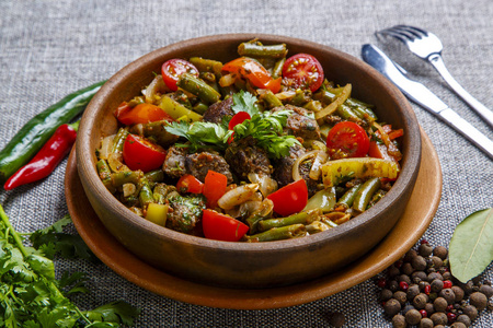 Chicken liver with vegetables on a clay plate. Pieces of liver, 