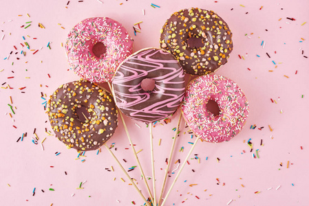 粉红色背景上有五彩纸屑的甜甜圈。创意美食极简风格
