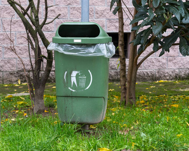 绿色垃圾桶存放在容器外的废物把纸扔到回收垃圾桶的人回收站带钱的