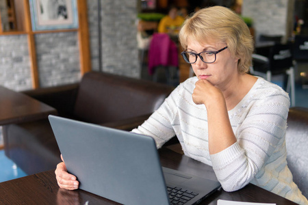 一个女人拿着笔记本电脑在咖啡馆办公室里看文件