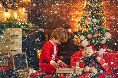 礼品盒。童年记忆。微笑的小男孩戴着圣诞老人的帽子在家里的圣诞树上。小圣诞老人小精灵，圣诞礼物。