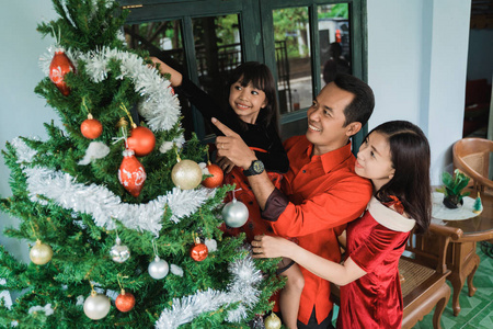家人和女儿挂着装饰圣诞树