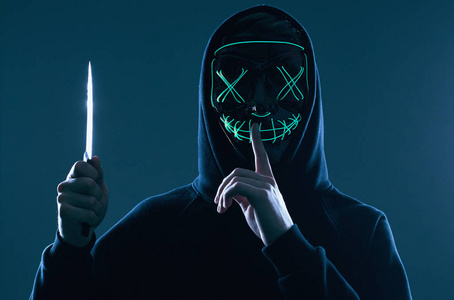 匿名黑客面具程序员使用笔记本电脑在黑暗中入侵系统.