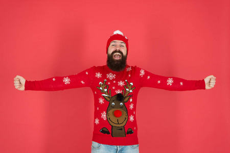 回家过节。在寒冷的季节取暖。冬装时尚。节日气氛。快乐圣诞老人的肖像。红墙上戴帽子的大胡子男人。成熟的时髦胡子在针织毛衣。