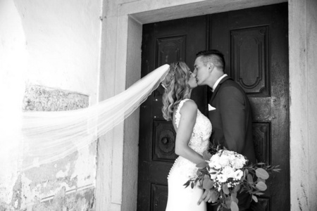 吻。新郎新娘在教堂大门前温柔地亲吻。