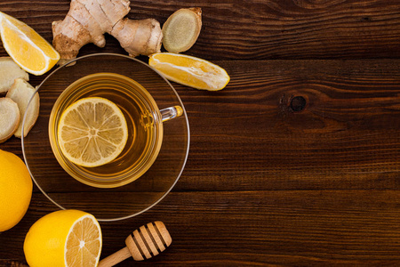 Cup of Ginger tea with lemon, honey and ginger root on a wooden 