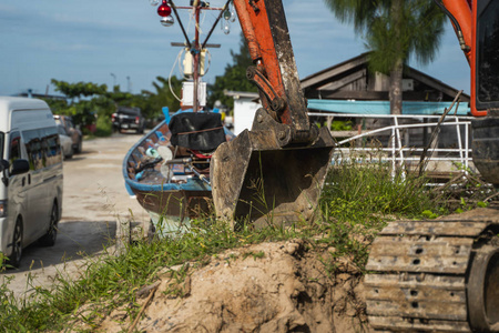 一台橙色的小型挖掘机在蓝天碧海的地面上进行施工。站在背景是蓝色海洋的地面上的小型履带式挖掘机。重工业。