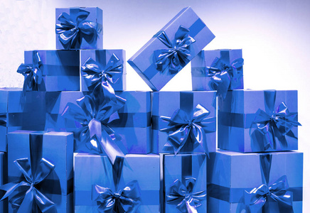 很多蓝色的礼盒,在浅色的墙壁背景上挂着节日彩带.