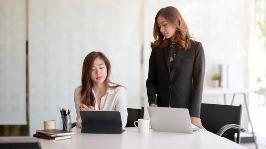 Portrait of two professional businesswomen discussing on their c