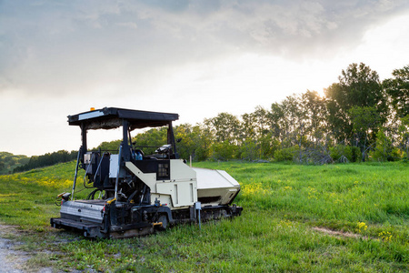 An paver machine for laying asphalt standing on the side of the 