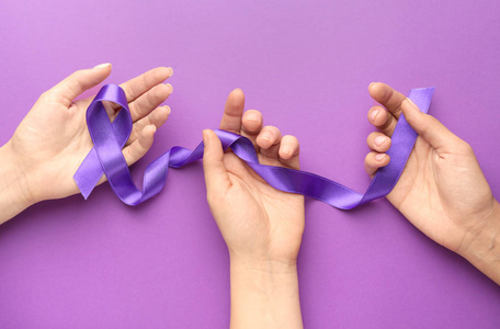 彩色背景上，紫色丝带象征世界癌症日的女性手