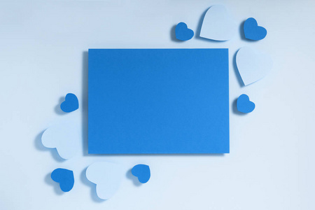 情人节相框构图。蓝色的心形白纸在柔和的背景上。俯视图，平面布置，复制空间
