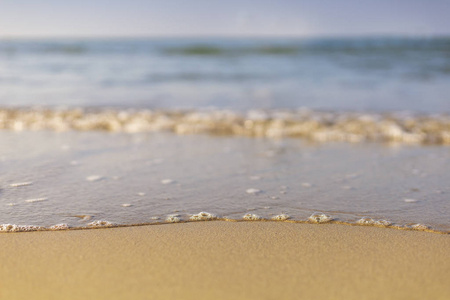 柔和的海浪从海上来到潮湿的沙滩上，天空背景模糊而清澈。有文本或设计的复制空间