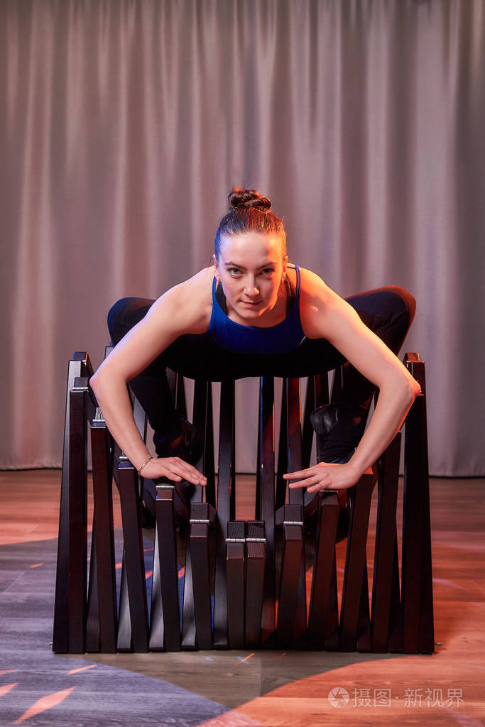 柔美的体操姑娘在大厅或舞台上用椅子做体操.