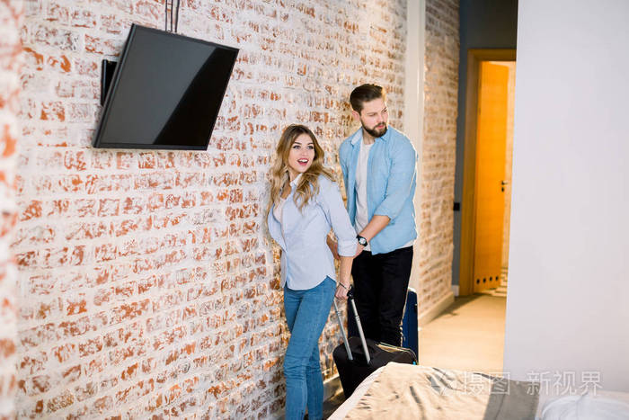 年轻的白人男女手牵手进入酒店的房间