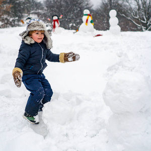 快乐的孩子和雪人在雪地里散步。白雪背景下的快乐孩子的冬季场景。冬天的孩子们。