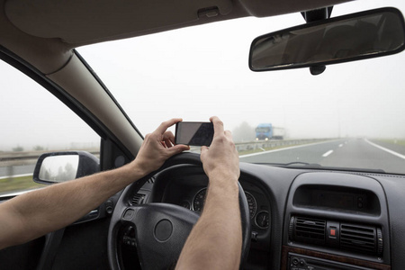 在车内使用智能手机。在高速公路上大雾中开车时用电话的人。