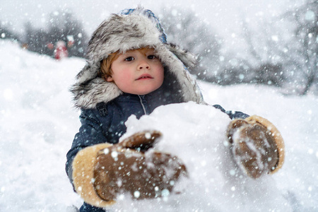 雪地里的圣诞孩子们。户外雪地上可爱的小男孩。小男孩在冬季公园玩得很开心。在阳光明媚的冬日里，快乐微笑的小男孩堆雪人。