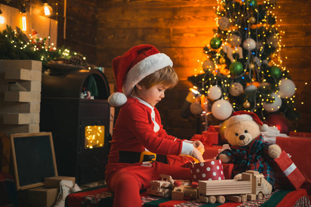 有趣的孩子拿着圣诞礼物。圣诞树旁可爱的小孩。冬季圣诞节的情感。新年圣诞概念。