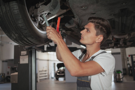 年轻英俊的汽车修理工在他的车库里修车