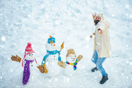 雪地里的圣诞老人。年轻时髦的冬季肖像。圣诞准备有趣的胡须人堆雪人。雪地里的人。雪人。有趣的冬季人物肖像。