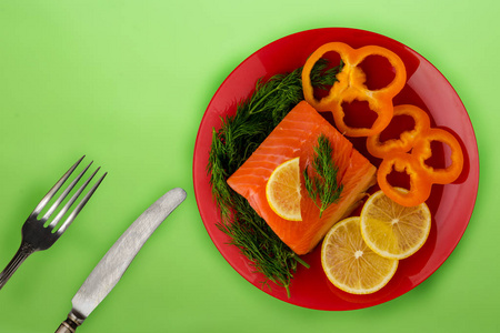 red fish with dill, pepper, lemon on a plate on the background. 