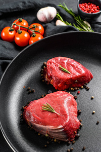 牛里脊肉牛排煎锅里的菲力牛排.牛里脊肉.黑色背景.俯视图照片