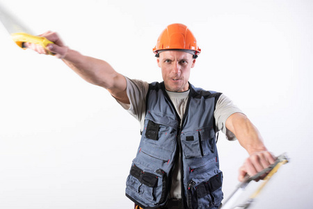 一个戴着钢锯的建筑工人在模仿。在一个浅色的背景上。