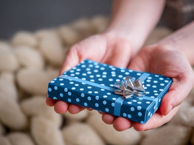 儿童手中的蓝色礼品盒，灰色蝴蝶结，羊毛背景