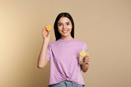 Beautiful young woman with tasty lemon water and fresh fruit on 