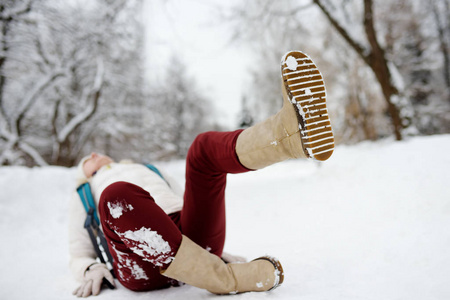 女人在冰冷的小路上滑了一跤,然后躺下了.照片