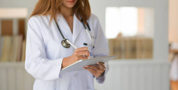 Cropped shot of young doctor checking patient chart while using 