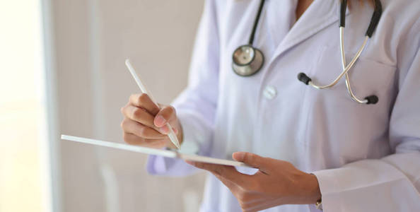 Cropped shot of young doctor checking patient chart while using 