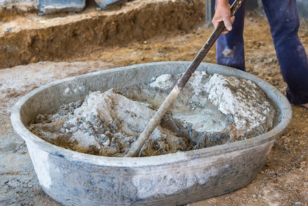 工人在施工现场用锄头在盆式搅拌机中混合水泥